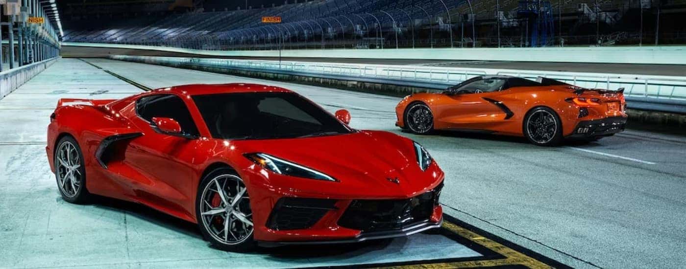 A red and an orange 2024 Chevy Corvette Stongray 3 LT Coupe are shown parked on a racetrack.