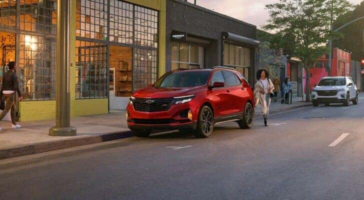 A red 2024 Chevy Equinox RS is shown parked near a store.