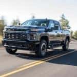 A grey 2020 Chevy Silverado 2500HD is shown from the front at an angle while it drives down the road.