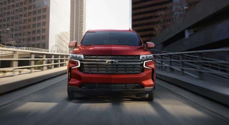 A red 2022 Chevy Tahoe is shown from the front driving through a city after leaving a Chevy dealership in Millbrook.