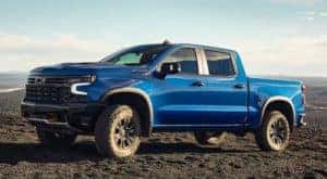 A blue 2022 Chevy Silverado 1500 ZR2 is shown driving on a dirt trail.