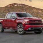 A red 2020 Chevy Silverado 1500 is shown from the side parked in front of a mountain.