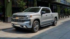 A silver 2019 Chevy Silverado 1500 is shown parked on the side of a city street.