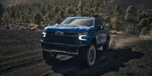 A blue 2023 Chevy Silverado ZR2 is shown off-roading after looking at Chevy trucks for sale.