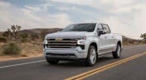 A white 2024 Chevy Silverado 1500 High Country is shown from the front at an angle.