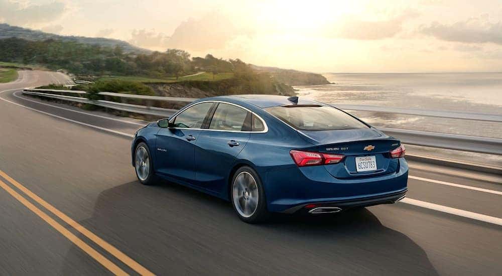 A blue 2020 Chevy Malibu is shown driving on a highway.