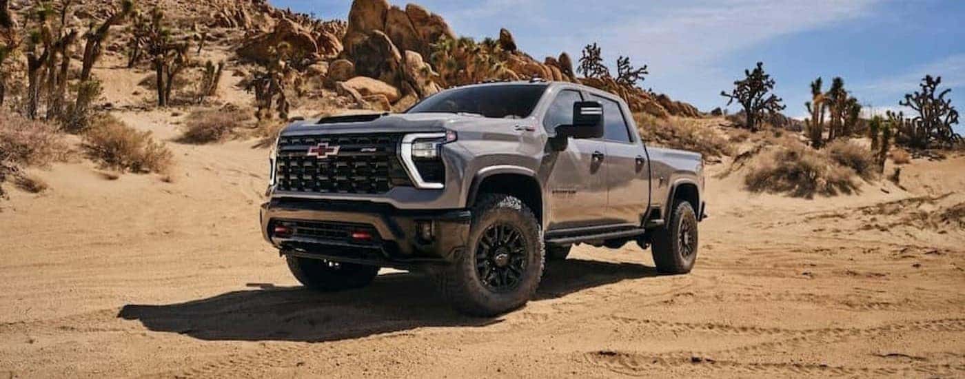 A gray 2024 Chevy Silverado 2500 ZR2 is shown parked on sand.