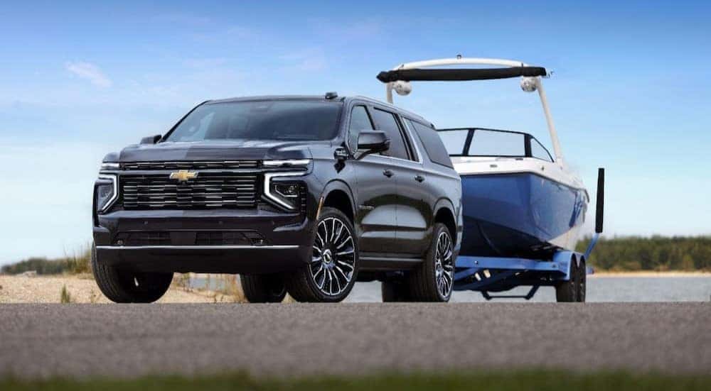 A blue 2025 Chevy Suburban is shown towing a boat.
