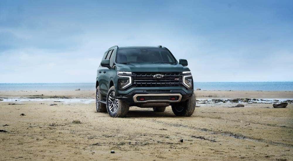 A green 2025 Chevy Tahoe Z71 is shown parked near an ocean.