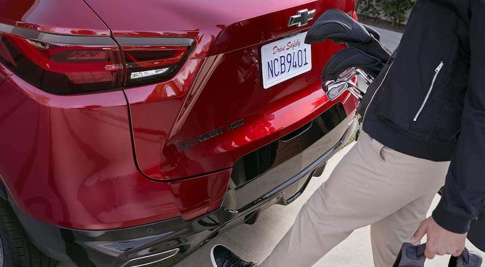 A close-up on a person opening the trunk of a red 2024 Chevy Blazer outside a Chevy dealer near Lagrangeville.
