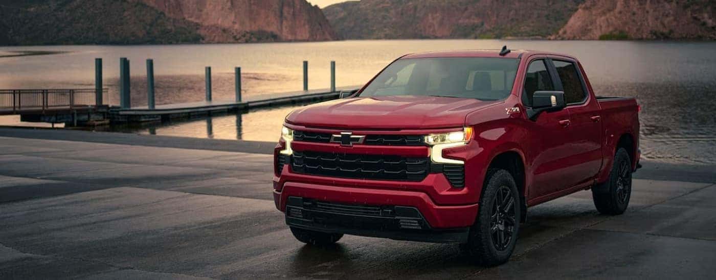 A red 2024 Chevy Silverado 1500 Z71 RST is shown parked near a lake.