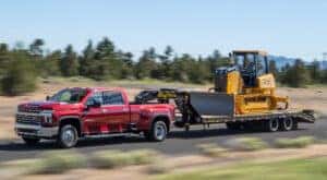 A red 2021 Chevy Silverado 3500 HD towing a bulldozer.