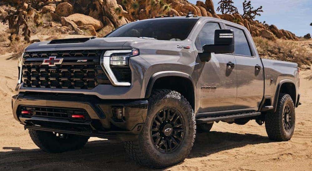 A grey 2024 Chevy Silverado ZR2 is shown from the front at an angle after leaving a dealer that has a Chevy Silverado for sale.