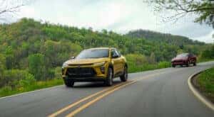 A yellow 2024 Chevy Trax ACTIV and a red Trax RS are shown rounding a corner.