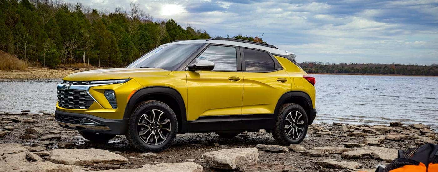 Left angled view of a yellow 2025 Chevy Trailblazer ACTIV parked by a lake.