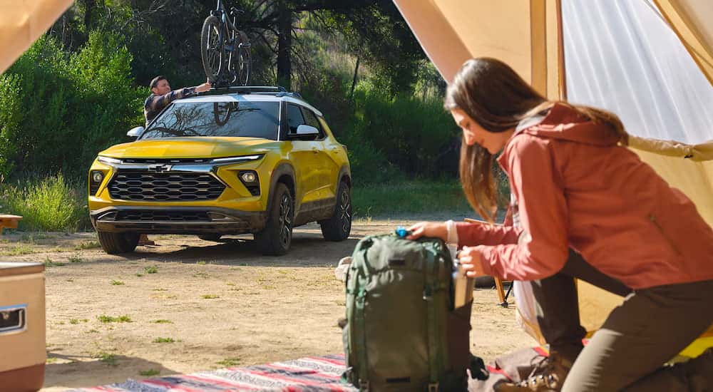 A yellow 2025 Chevy Trailblazer ACTIV parked by a campsite.