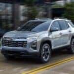 A silver 2025 Chevy Equinox for sale in Millbrook driving down a road.