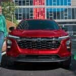 Two women walking away from a red 2025 Chevy Trax 2RS.