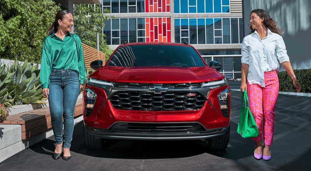 Two women walking away from a red 2025 Chevy Trax 2RS.