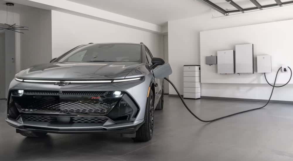 Silver 2025 Chevy Equinox EV charging in a garage.