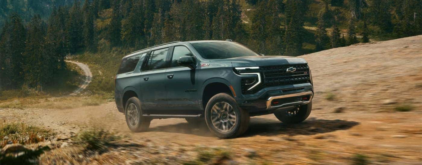 A green 2025 Chevy Suburban Z71 driving to a Chevrolet dealer.