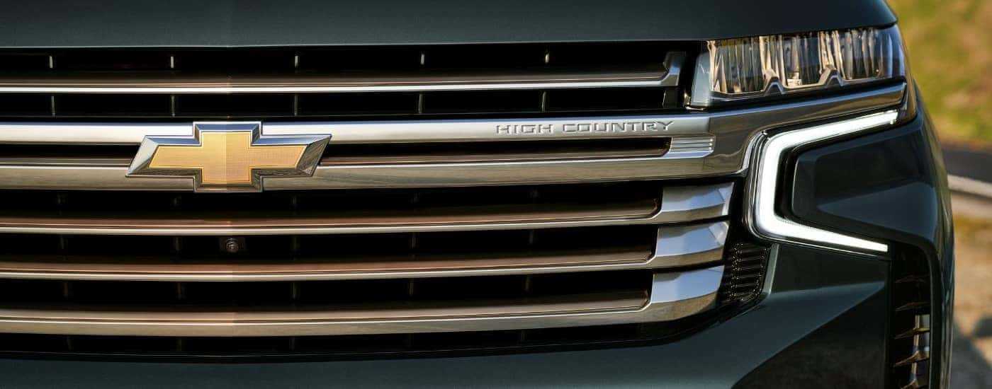 A close up shows the driver side headlight and grille on a dark green 2022 Chevy Tahoe High Country.