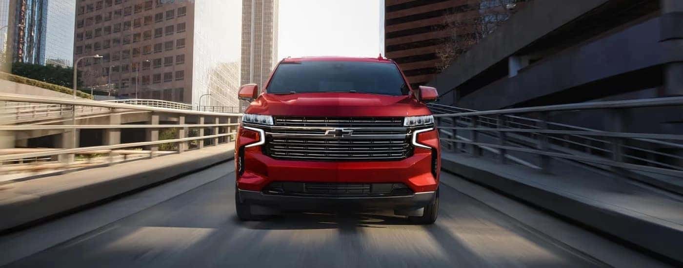 A red 2022 Chevy Tahoe is shown from the front driving through a city after leaving a Chevy dealership in Millbrook.