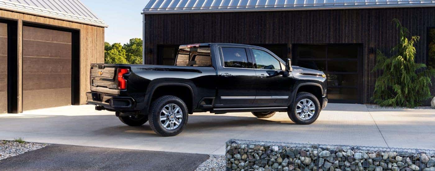A black 2024 Chevy Silverado 2500 HD is shown from the side while parked in a driveway.