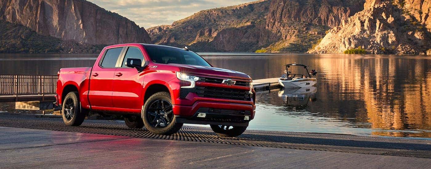 A red 2024 Chevy Silverado 1500 RST is shown parked near a lake after viewing a Chevy Silverado for sale.