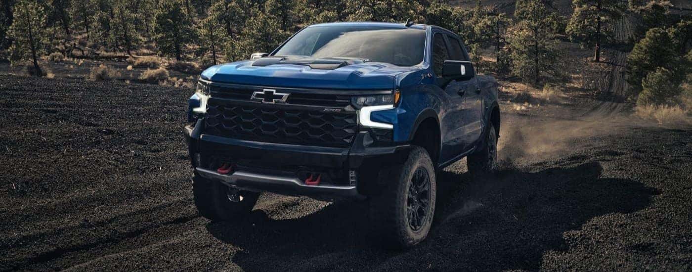 A blue 2023 Chevy Silverado ZR2 is shown off-roading after looking at Chevy trucks for sale.