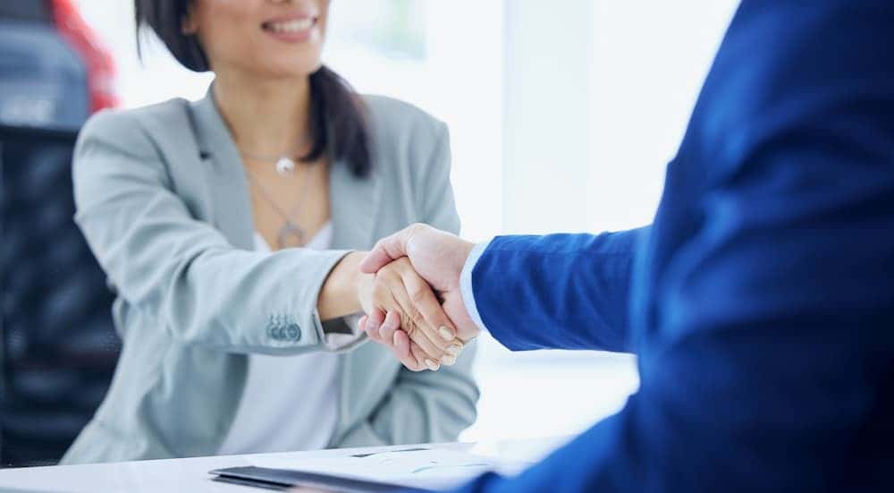 Two people shaking hands over paperwork.