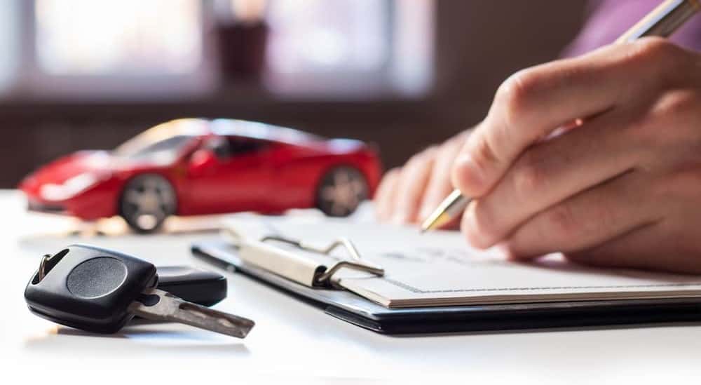 A person signing paperwork after trying to "sell my car".