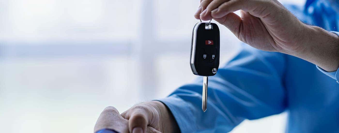 A man shaking hands and giving over a car key