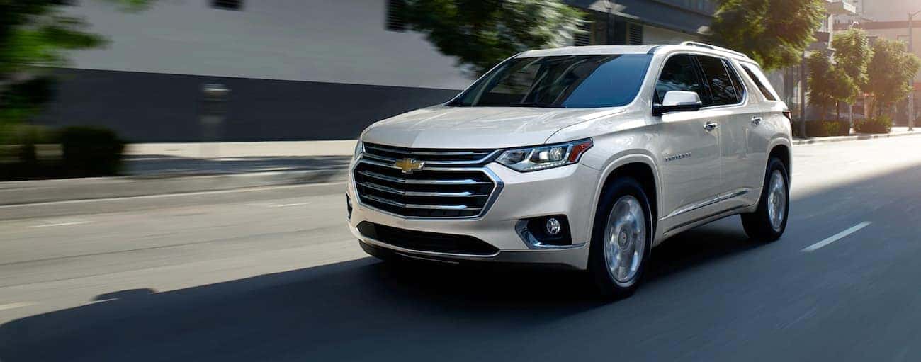 A white 2020 Chevy Traverse is shown leaving a used Chevy dealership.