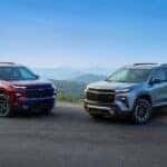 A red 2025 Chevy Traverse RS and a silver 2025 Chevy Traverse Z71 for sale parked off-road