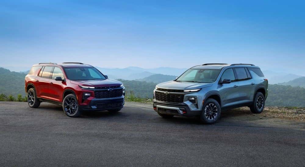 A red 2025 Chevy Traverse RS and a silver 2025 Chevy Traverse Z71 for sale parked off-road