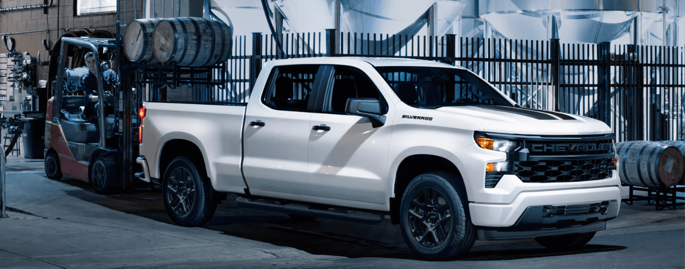 White 2025 Chevy Silverado 1500 Rally Edition with barrels being loaded into the bed