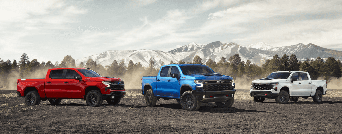 A red, a blue, and a white 2026 Chevy Silverado 1500 parked side by side