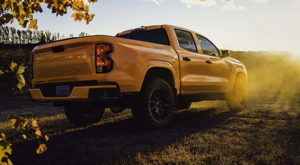 Rear and side of a yellow 2026 Chevy Colorado parked near a field