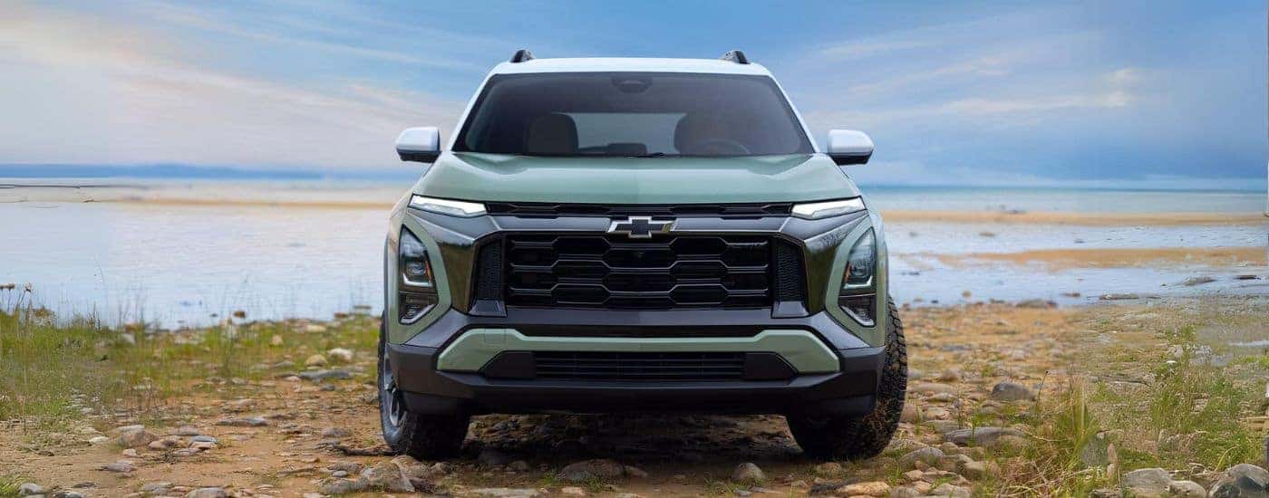 A green 2025 Chevy Equinox ACTIV front-view parked on a beach.