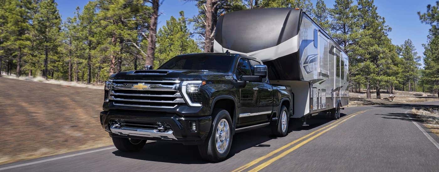 Black 2026 Chevy Silverado 2500 towing a camper.