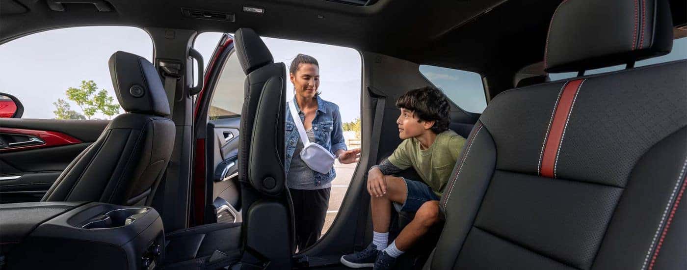 A mother folding down the 2nd row seats for her child to exit the 3rd row in a 2026 Chevy Traverse.