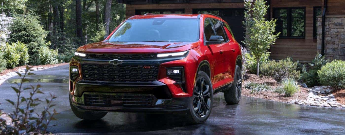 A red 2027 Chevy Traverse RS parked in a wet driveway.