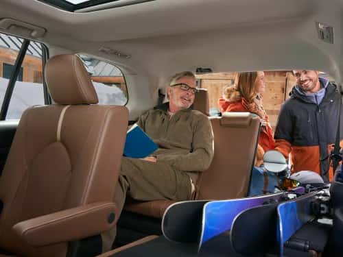 2025 Toyota Grand Highlander view of man in back seat and couple loading ski supplies in cargo area