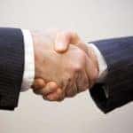 Two men shaking hands wearing business suits.