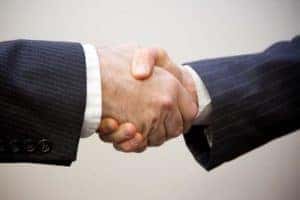 Two men shaking hands wearing business suits.