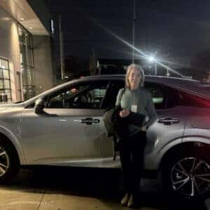 woman standing to side of SUV at night