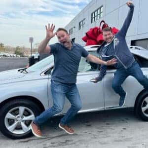 Guys jumping midair in front of New Vehicle