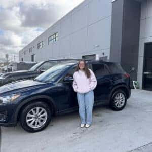 Woman with pink Sweater in front of new car