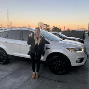 woman holding key with new car